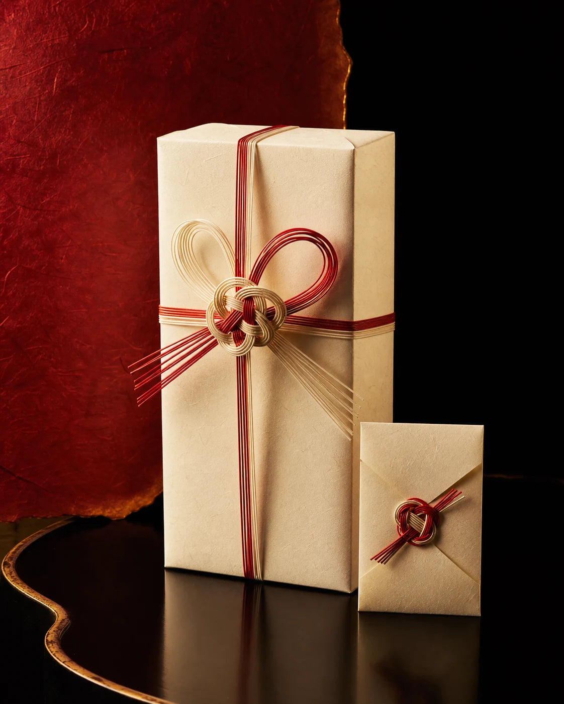 An ivory washi sake gift box tied with red and gold mizuhiki cord
