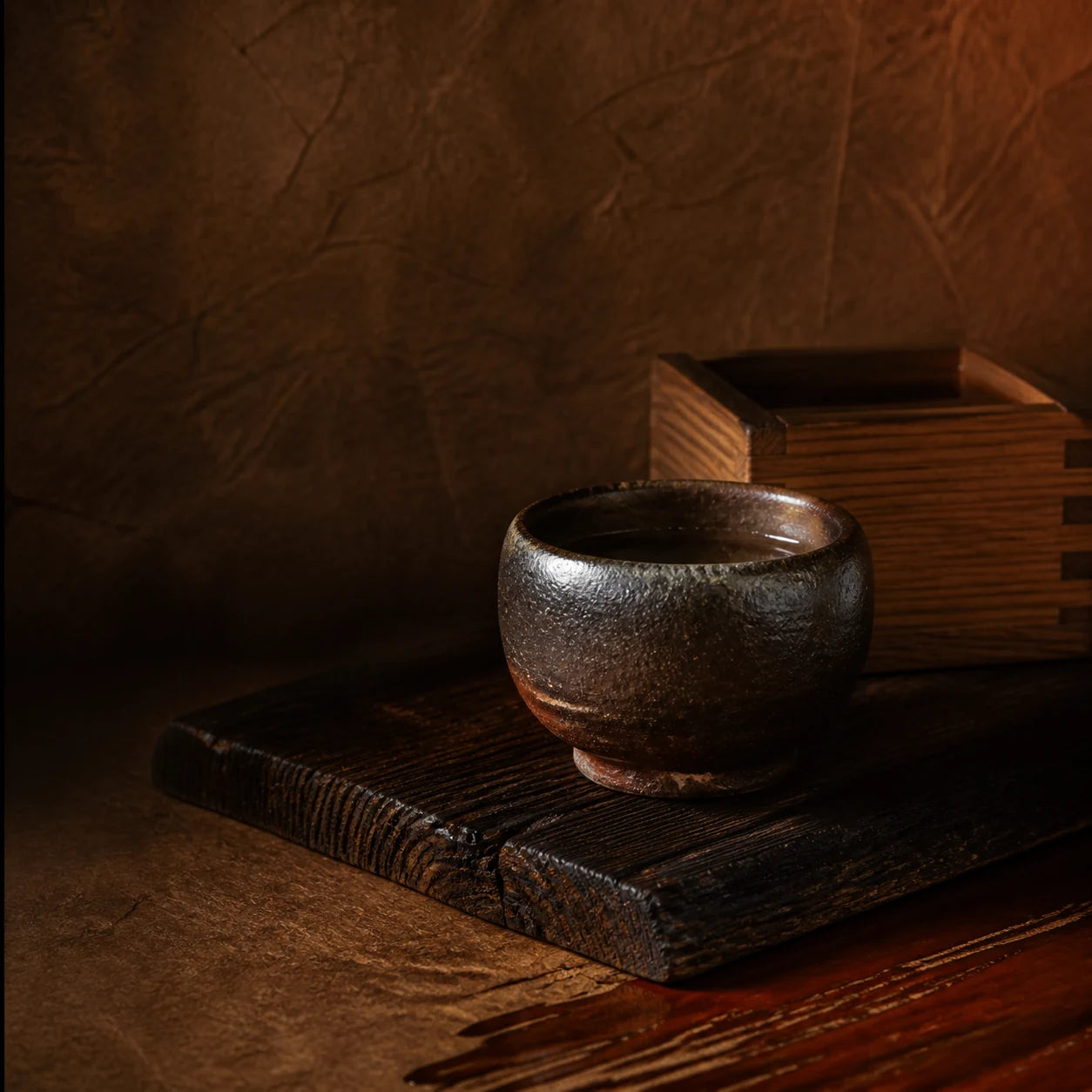 A substantial Bizen ceramic sake cup on dark cedar