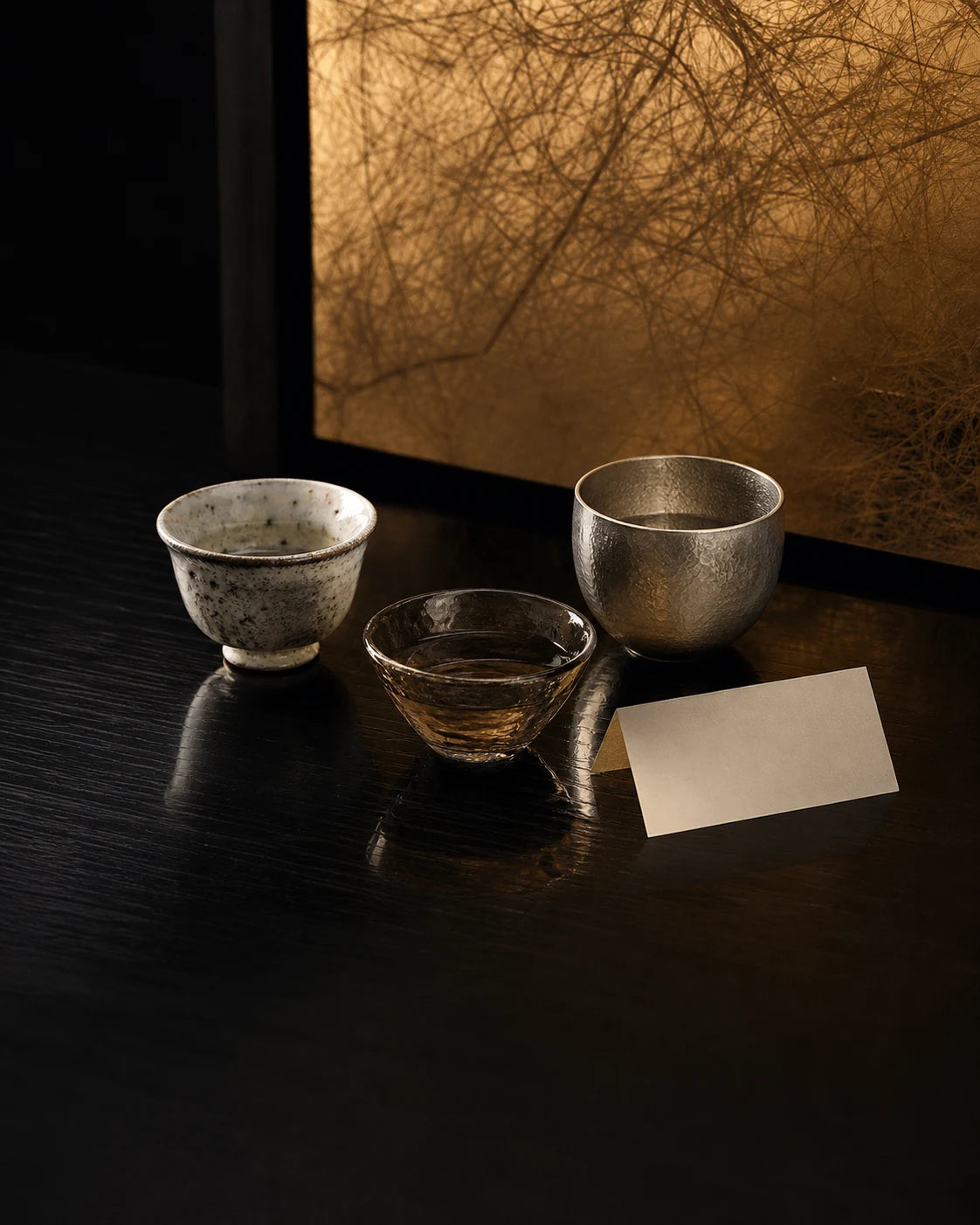 A curated tasting flight of ceramic, glass, and hammered metal sake cups