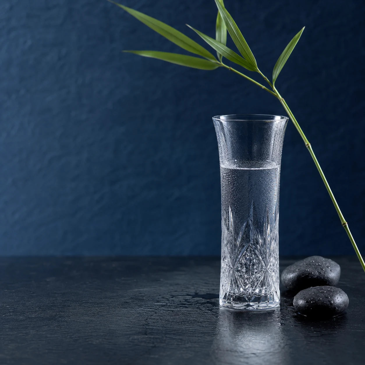 A chilled cut-glass sake vessel with bamboo and wet river stones